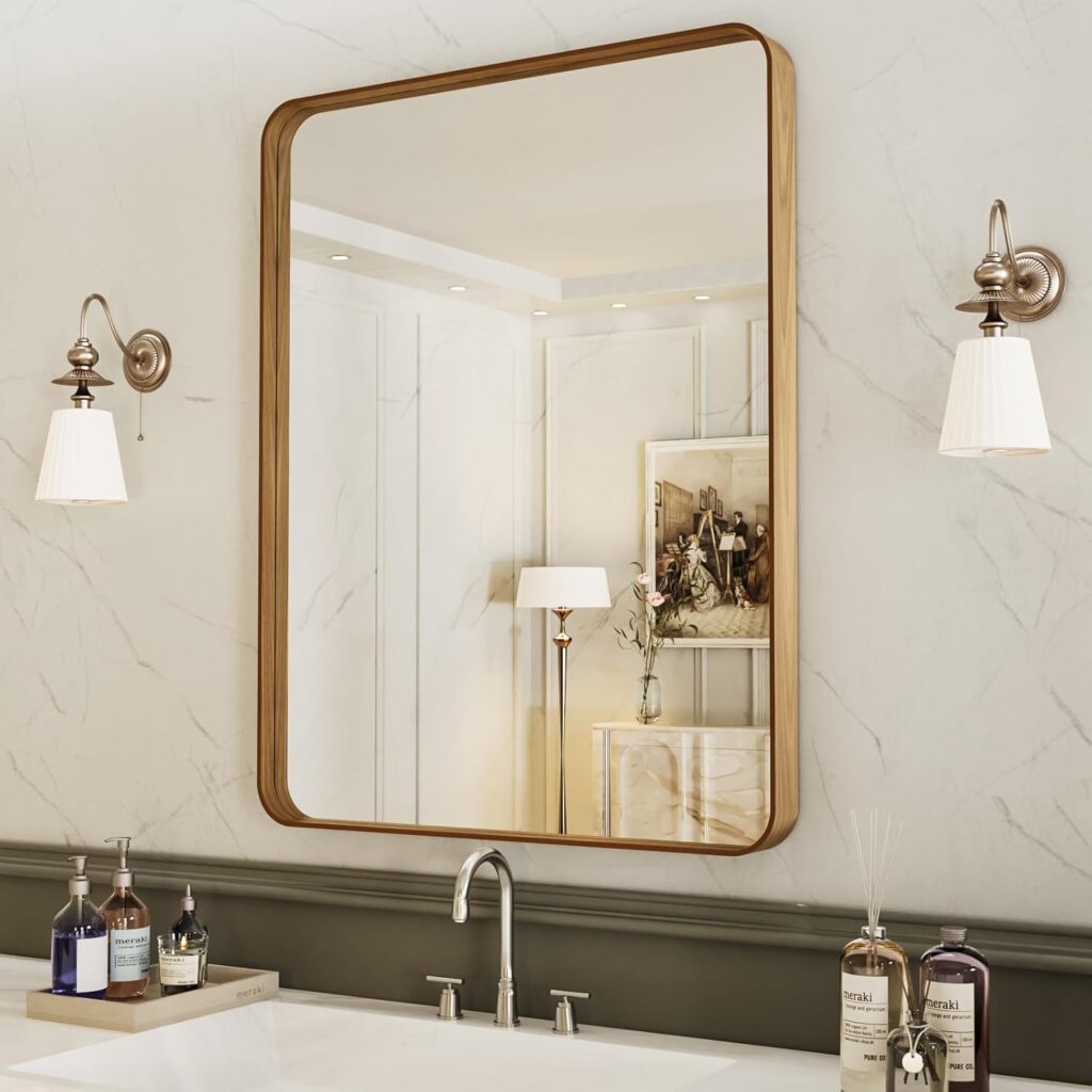 rectangular brass framed mirror with wall sconces in neutral bathroom