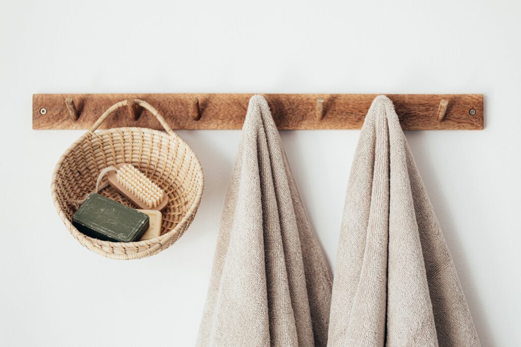 an organized bathroom hook with towels hanging and a basket with a brush and soap inside