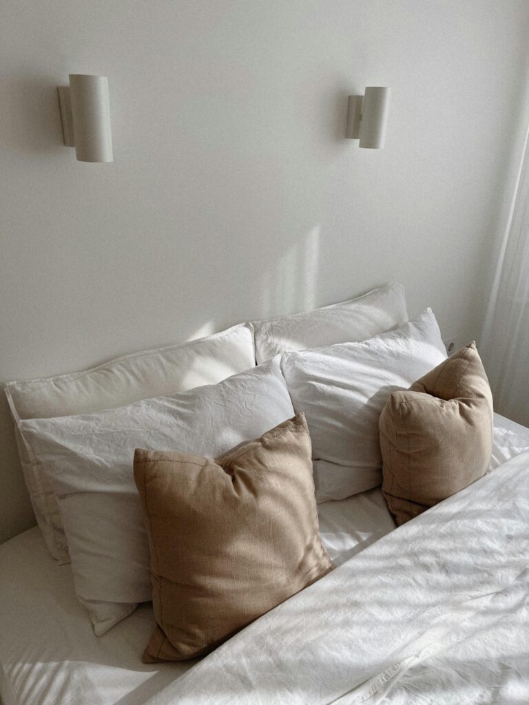 minimal bedroom with white scone wall lighting and white bedding