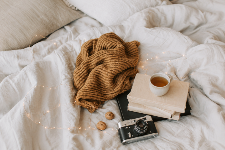 fall bedroom decor with a throw blanket on the bed with a camera and coffee