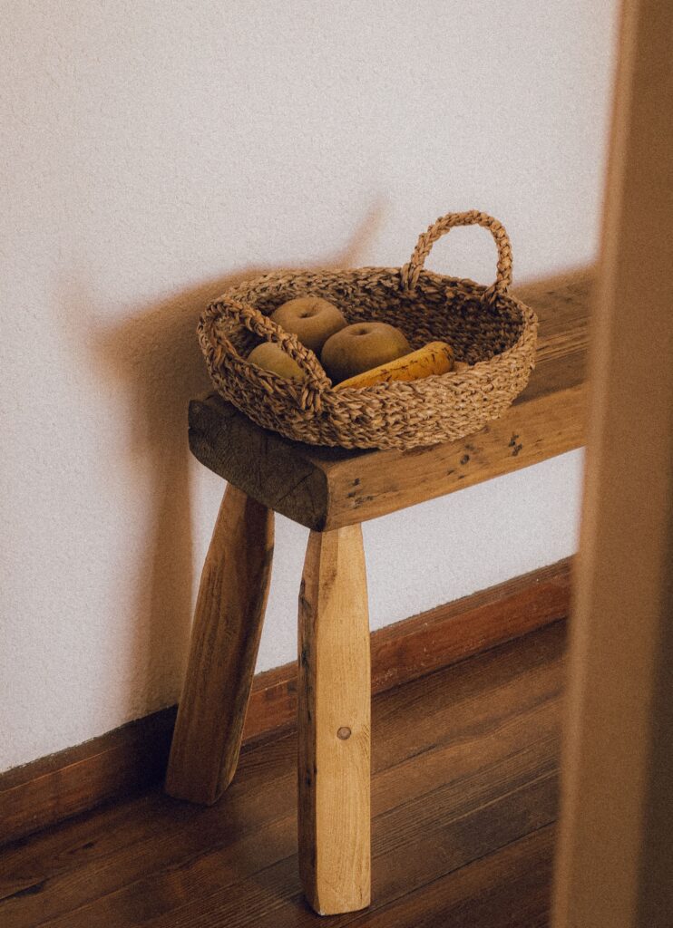 natural wood bench in bedroom with woven basket and dried apples in the basket