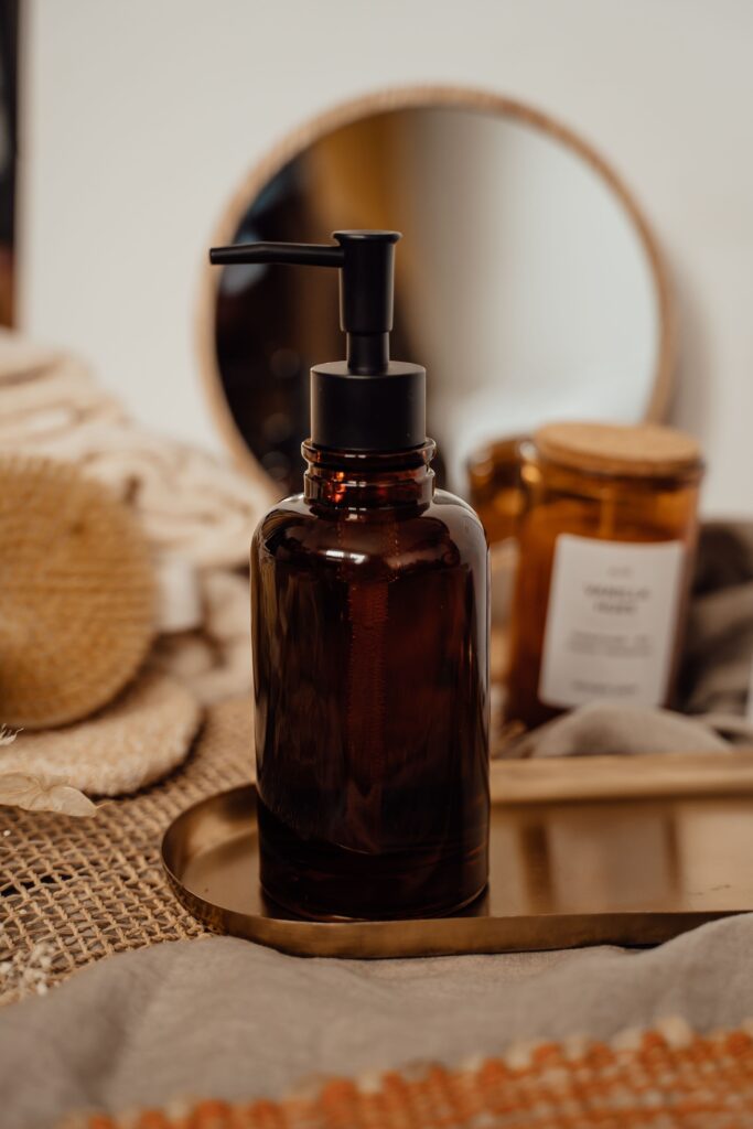amber glass soap dispenser with a candle in the back