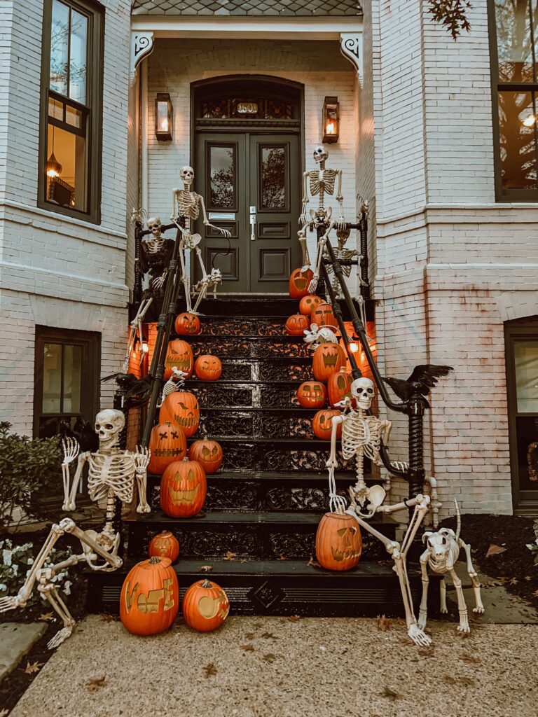 pumpkins and skeletons on a staircase in front of a front porch