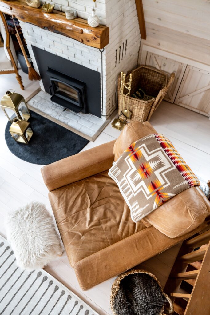 layered warm textures in a living room with a brown leather couch and a cozy throw blamket