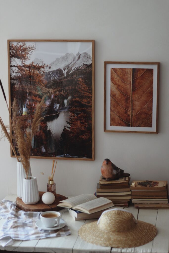 a decorated fall living room with 2 photographs on the wall and a vase holding dried flowers