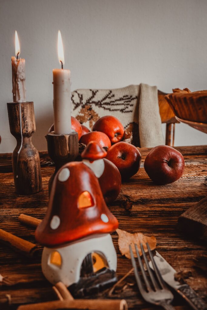 Ceramic Mushroom homes on kitchen table with lit candles and apples on kitchen table for Fall Kitchen Decor