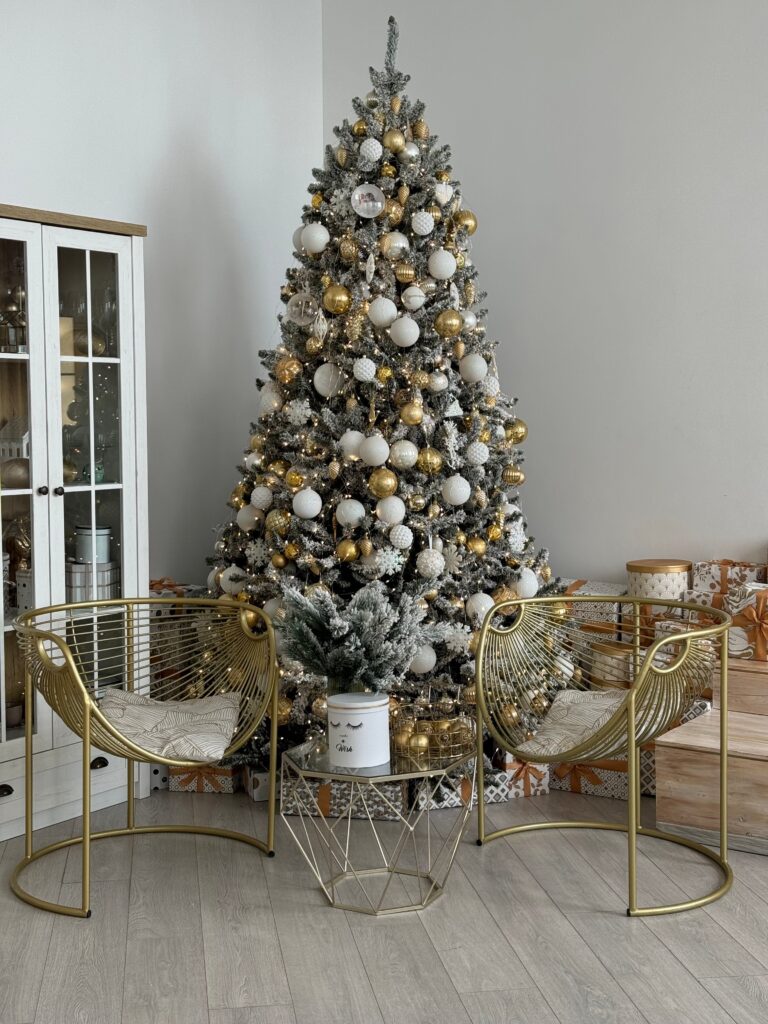 "Modern Christmas tree decoration ideas featuring a flocked tree with white and gold ornaments in a bright, contemporary living room."